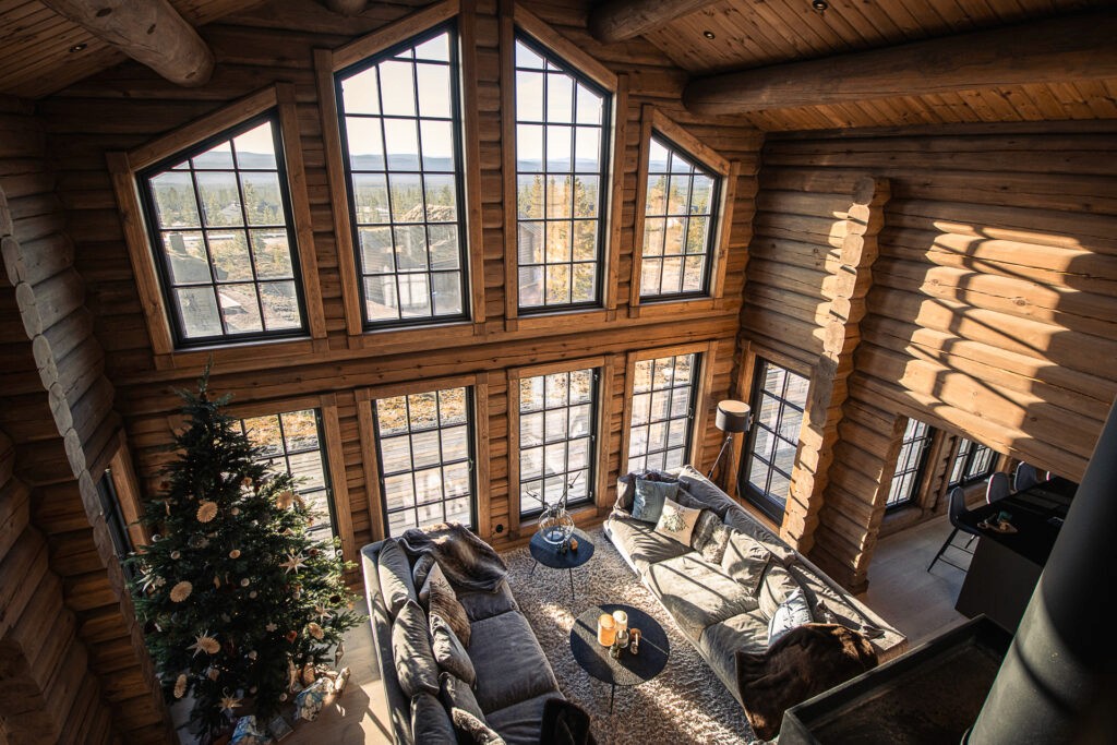 Log cabin living room with a Christmas tree, rustic wooden walls, and cozy holiday decorations.