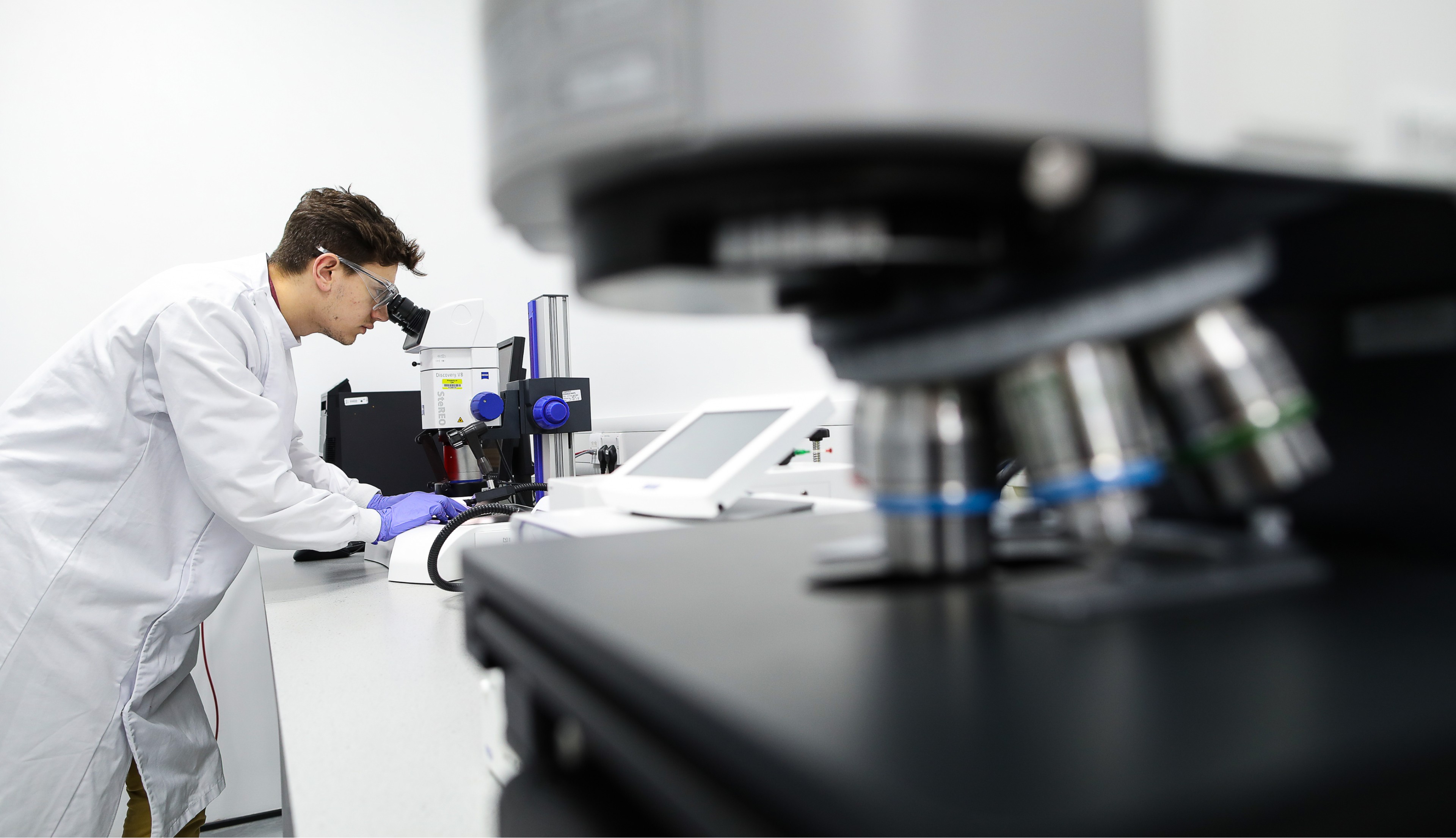 A photo of a young scientist in the lab looking through a microscope