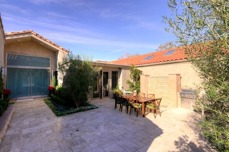 Outdoor courtyard with dining area and olive trees at Harbor Ridge Transitional Remodel.