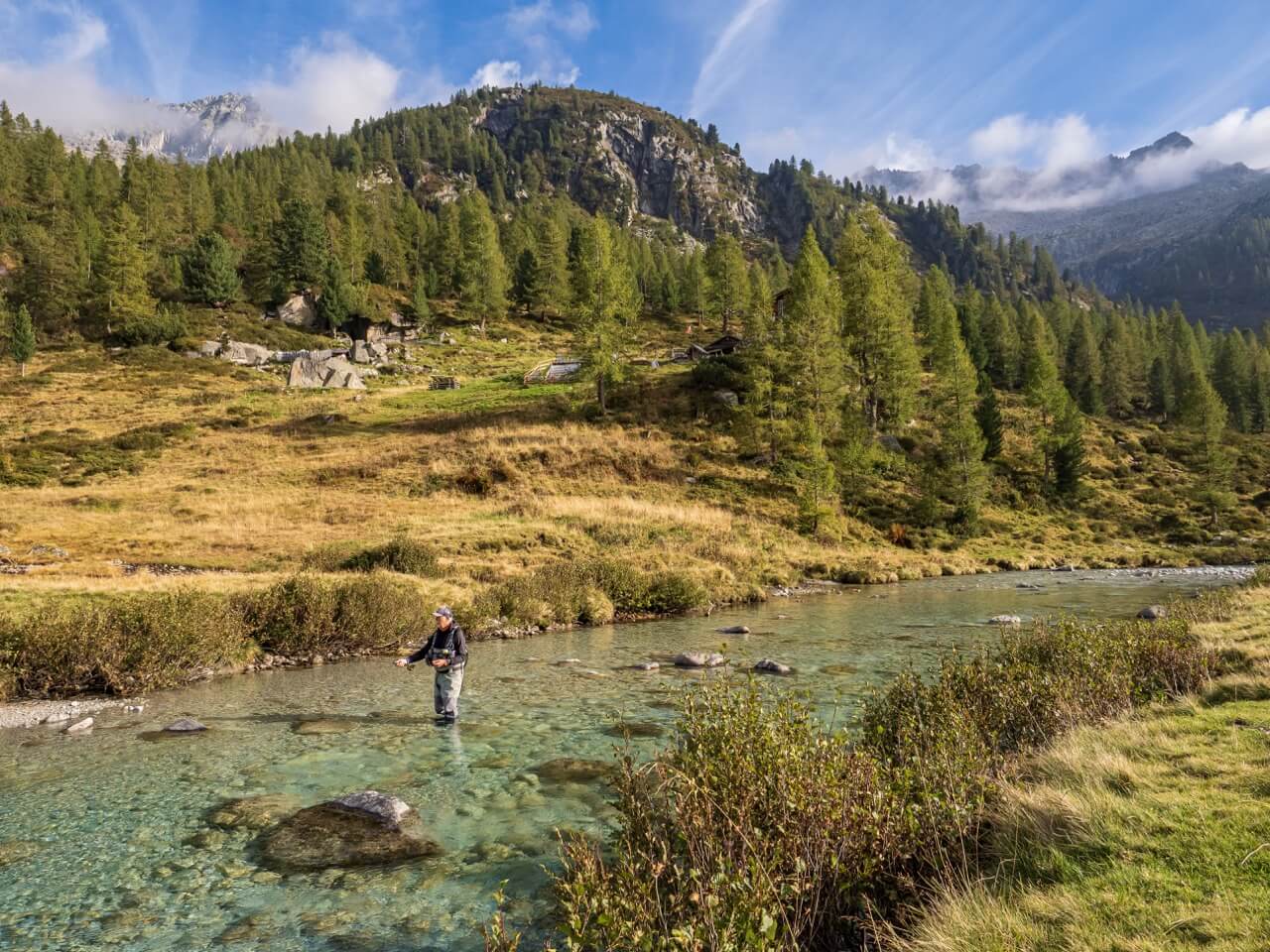 Fly fishing in Italy on a peaceful river in Tuscany or Umbria, featuring a fisherman casting a dry fly for brown trout and wild trout in clear blue waters, surrounded by the scenic countryside. Perfect spot for alpine fishing adventures