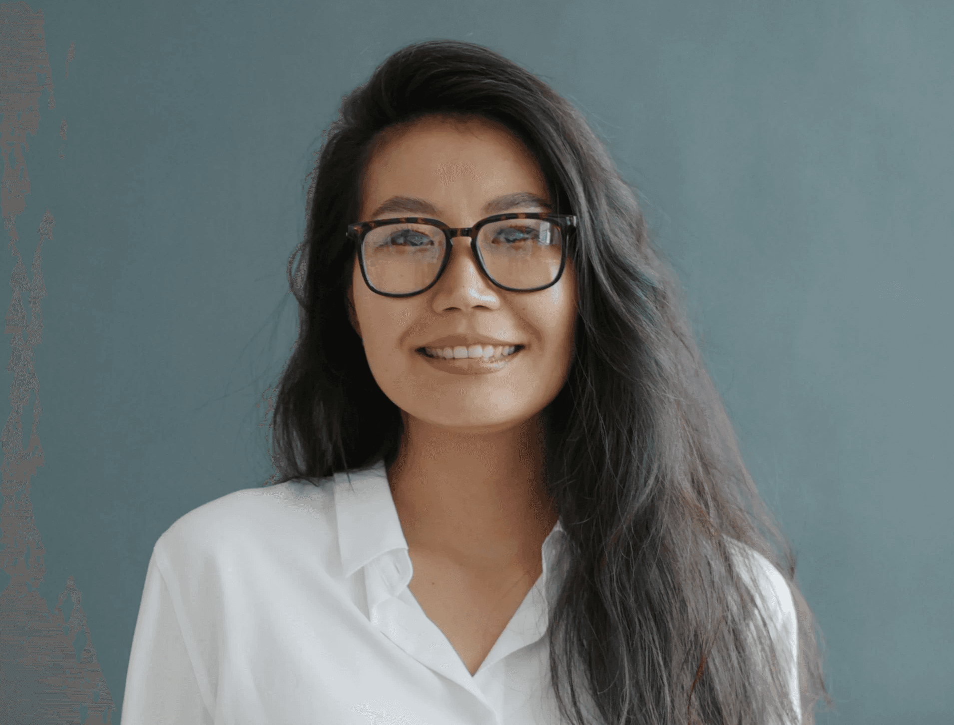 portrait of a woman with long dark hair wearing glasses and a light sweater.