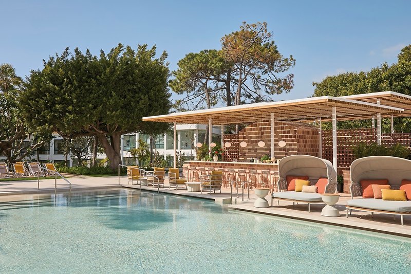 Luxuriöser Poolbereich mit Bar, Liegen und Bäumen an einem sonnigen Tag.