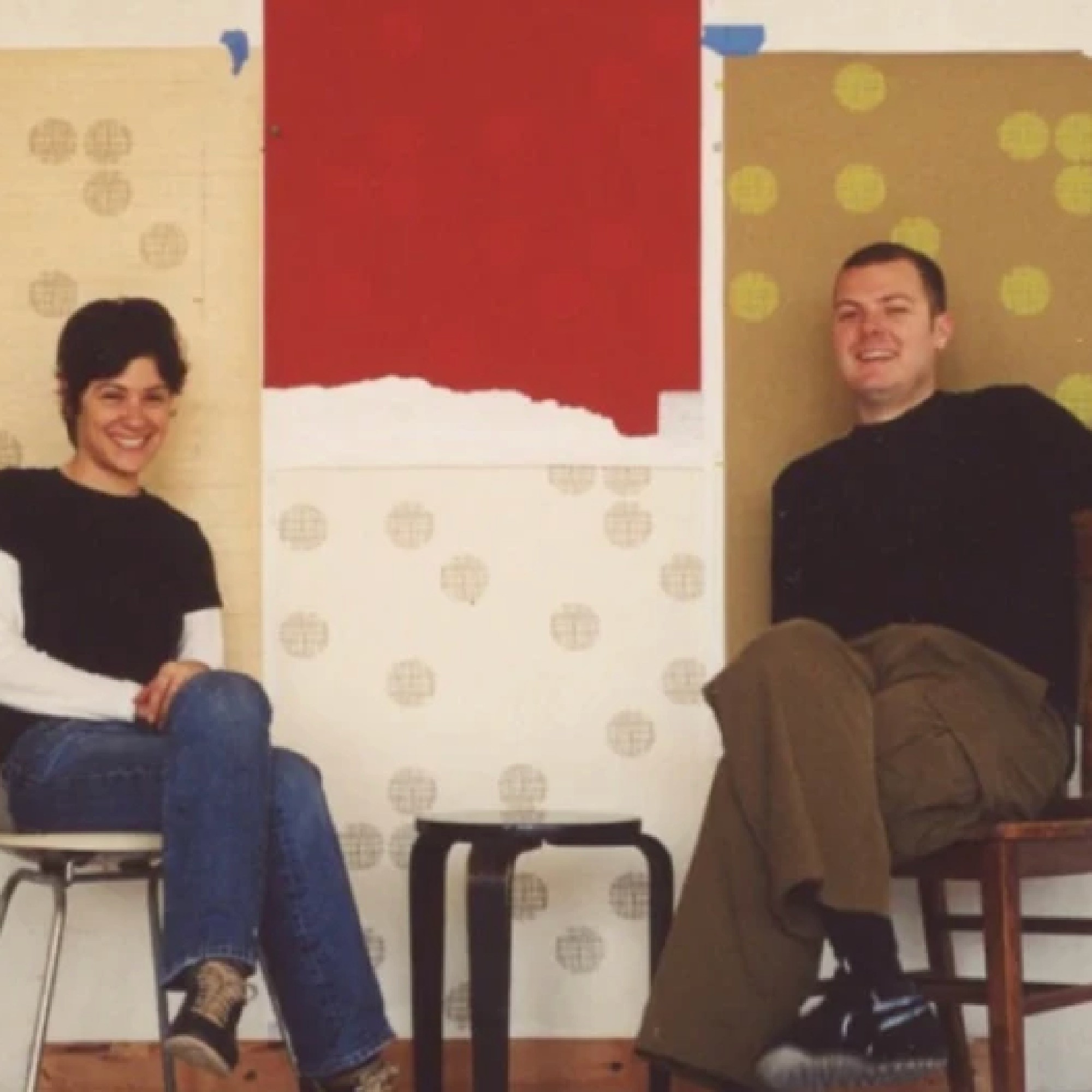 Young Kyra and Rob Hartnett posing in front of multiple pieces of their screen printed wallpaper.