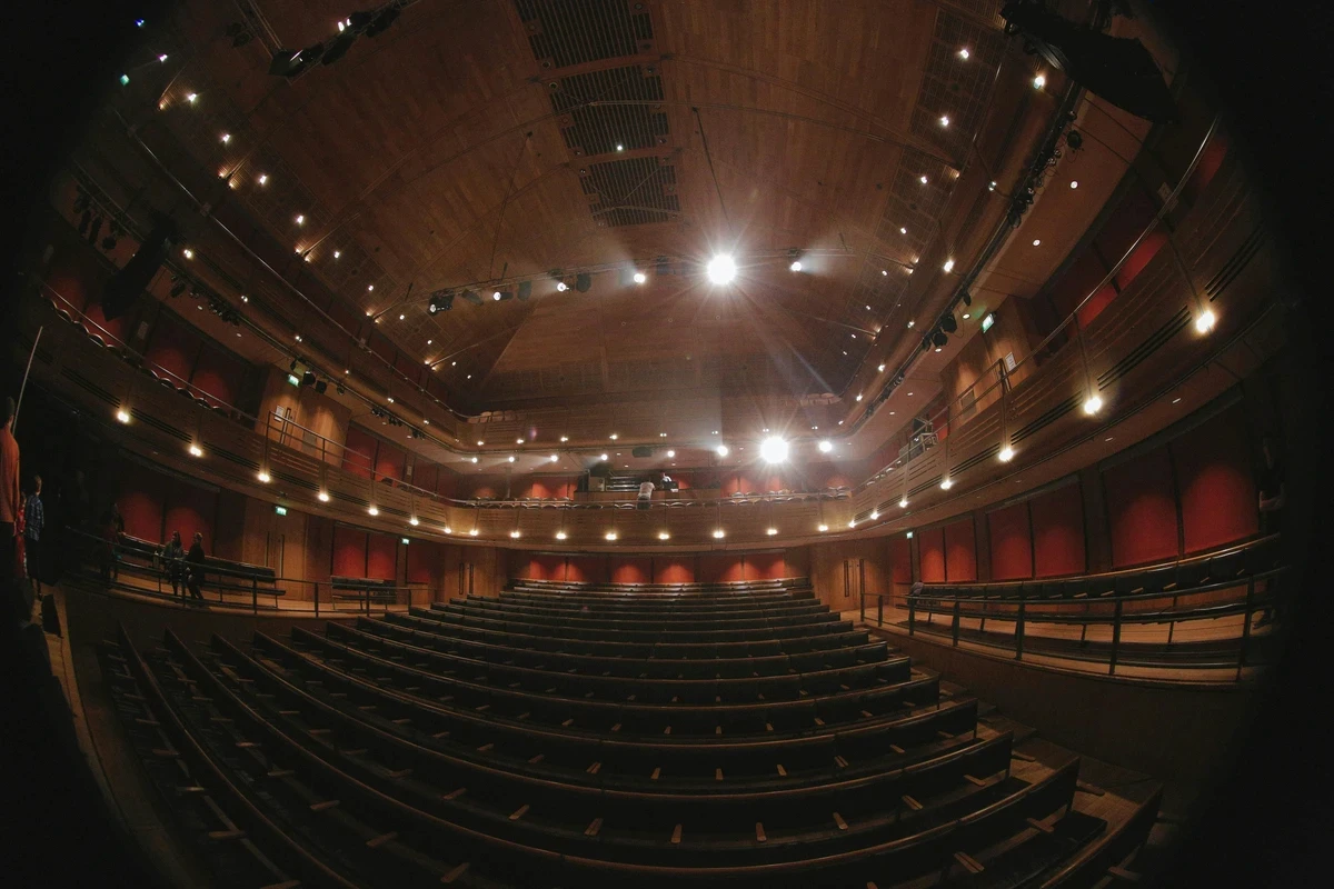 Wide shot of an empty concert hall with tiered seating and warm lighting.