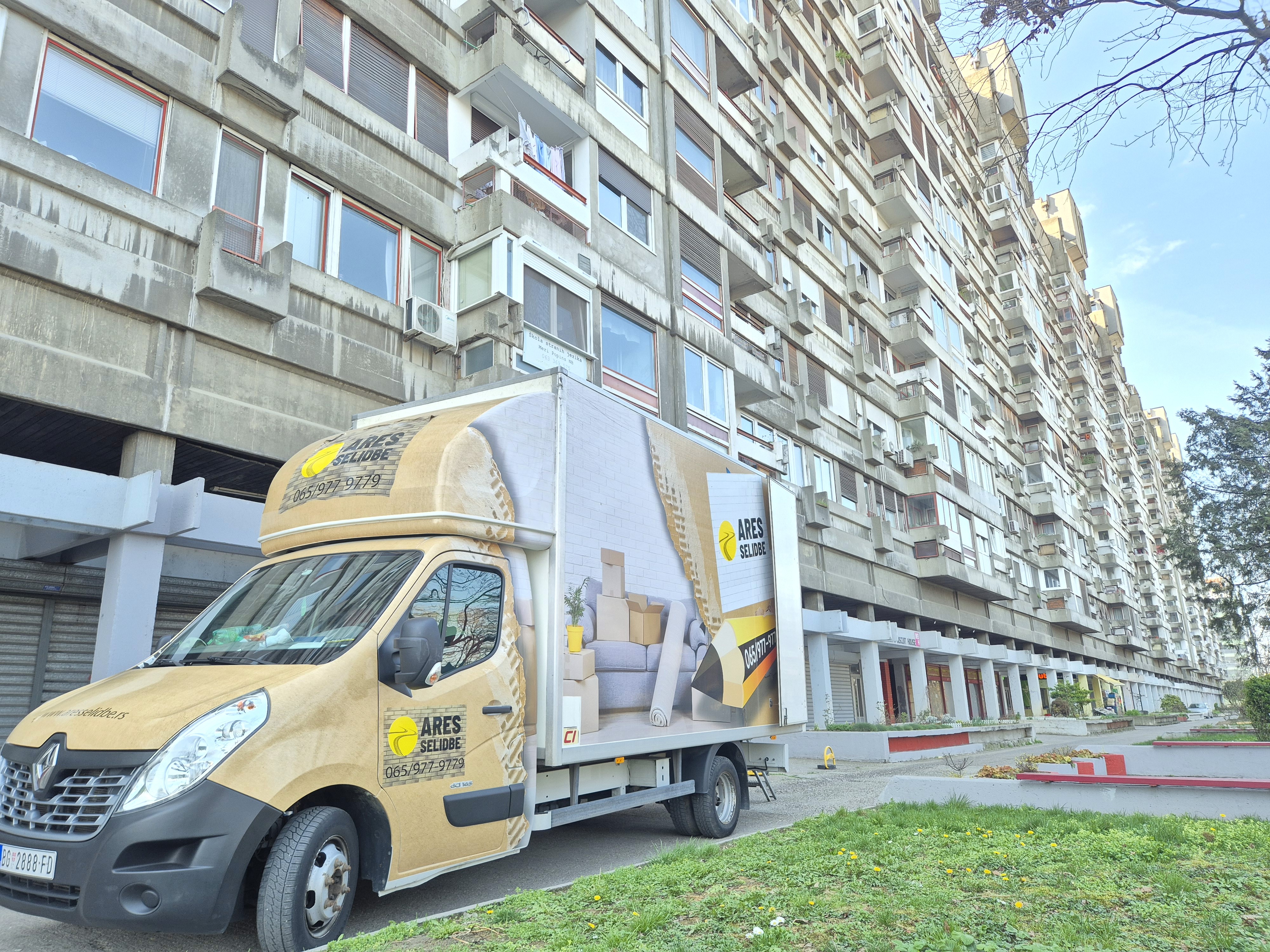 Kombi za selidbe „Ares Selidbe” parkiran ispred velike stambene zgrade