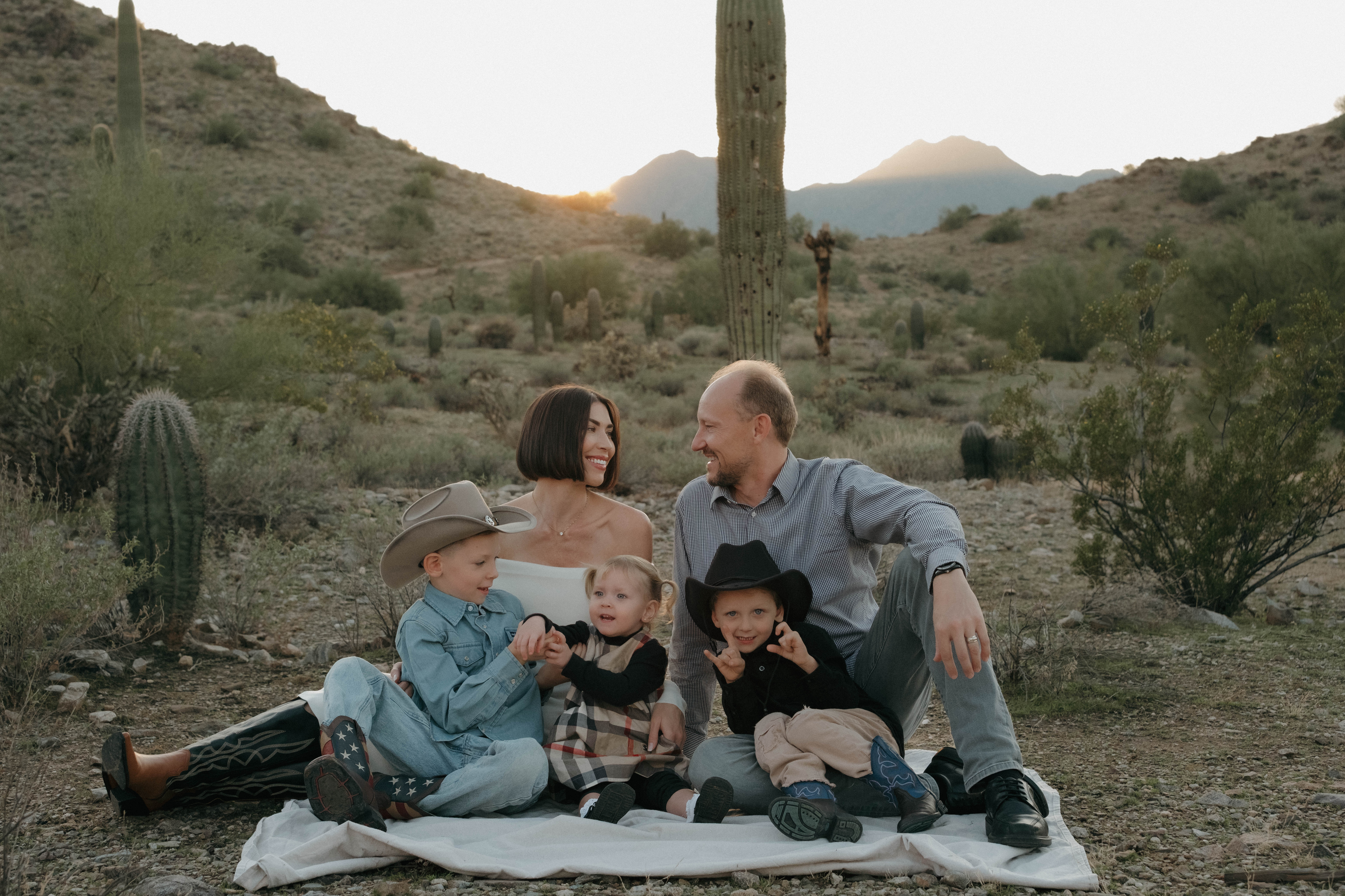 Couple holding hands and displaying ultrasound photos in a desert landscape during a pregnancy announcement photoshoot in Chandler, Arizona.