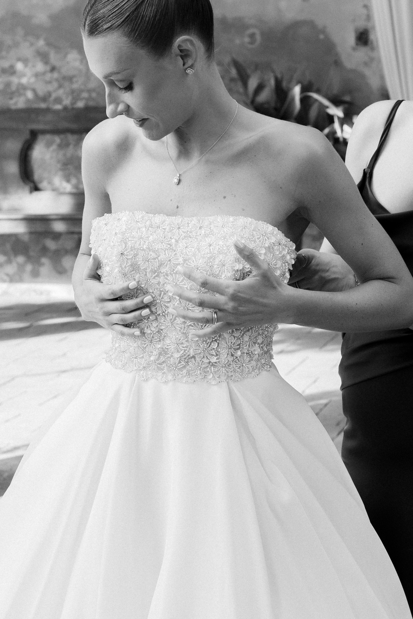 Sposa in abito ricamato guarda verso il basso durante i preparativi a Villa Ferrari, reportage di matrimonio