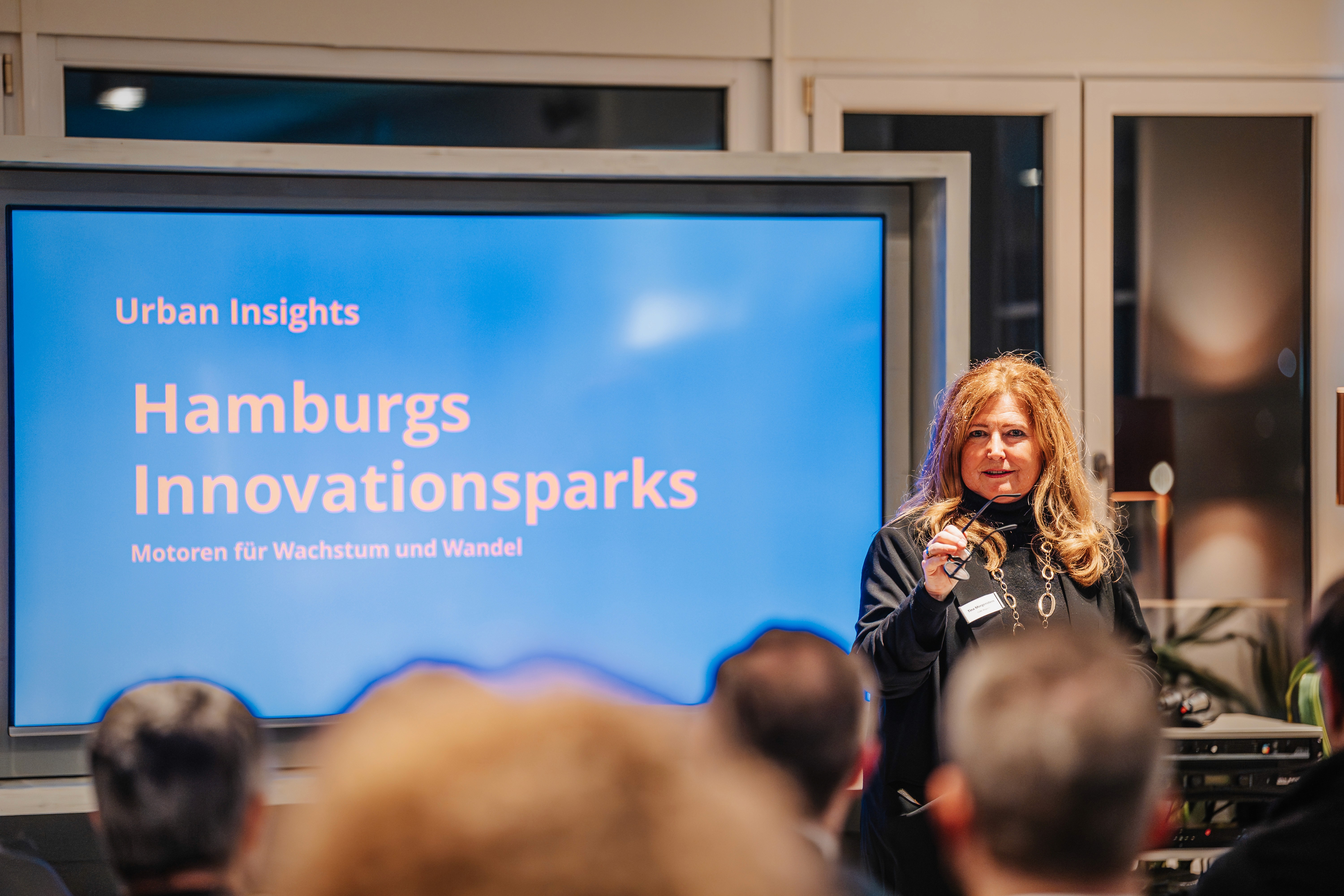 People crossing a busy street with cars and buildings.