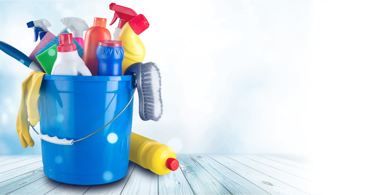 A blue container filled with various cleaning supplies like sprays, brushes, and cloths against a light background.