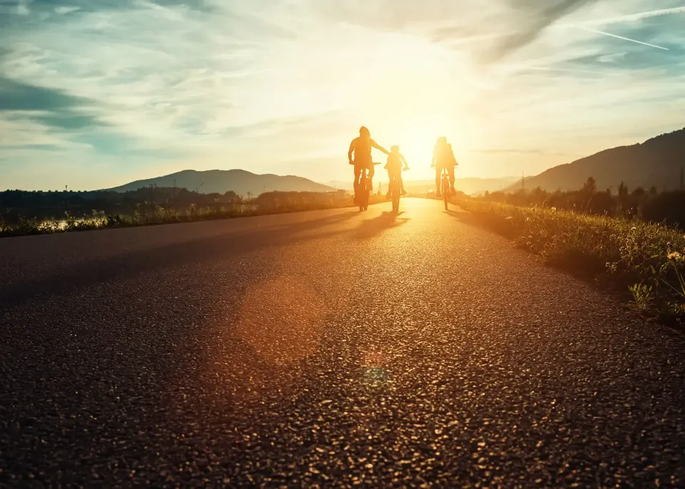 Familia paseando en bicicleta al atardecer disfrutando de tranquilidad financiera. Tus asesores en seguros de ahorro Allianz Plazo Flexible en Murcia Centro: saca el dinero parado de tu banco y hazlo crecer mediante un interés fijo, 100% garantizado y respaldado por la mayor gestora europea.
