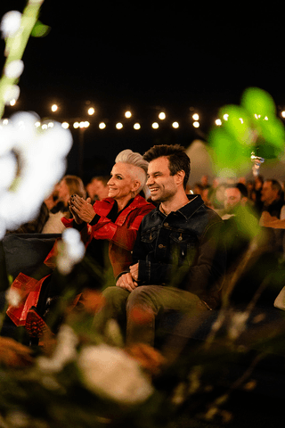 A person with short blonde hair holds a vintage camera.