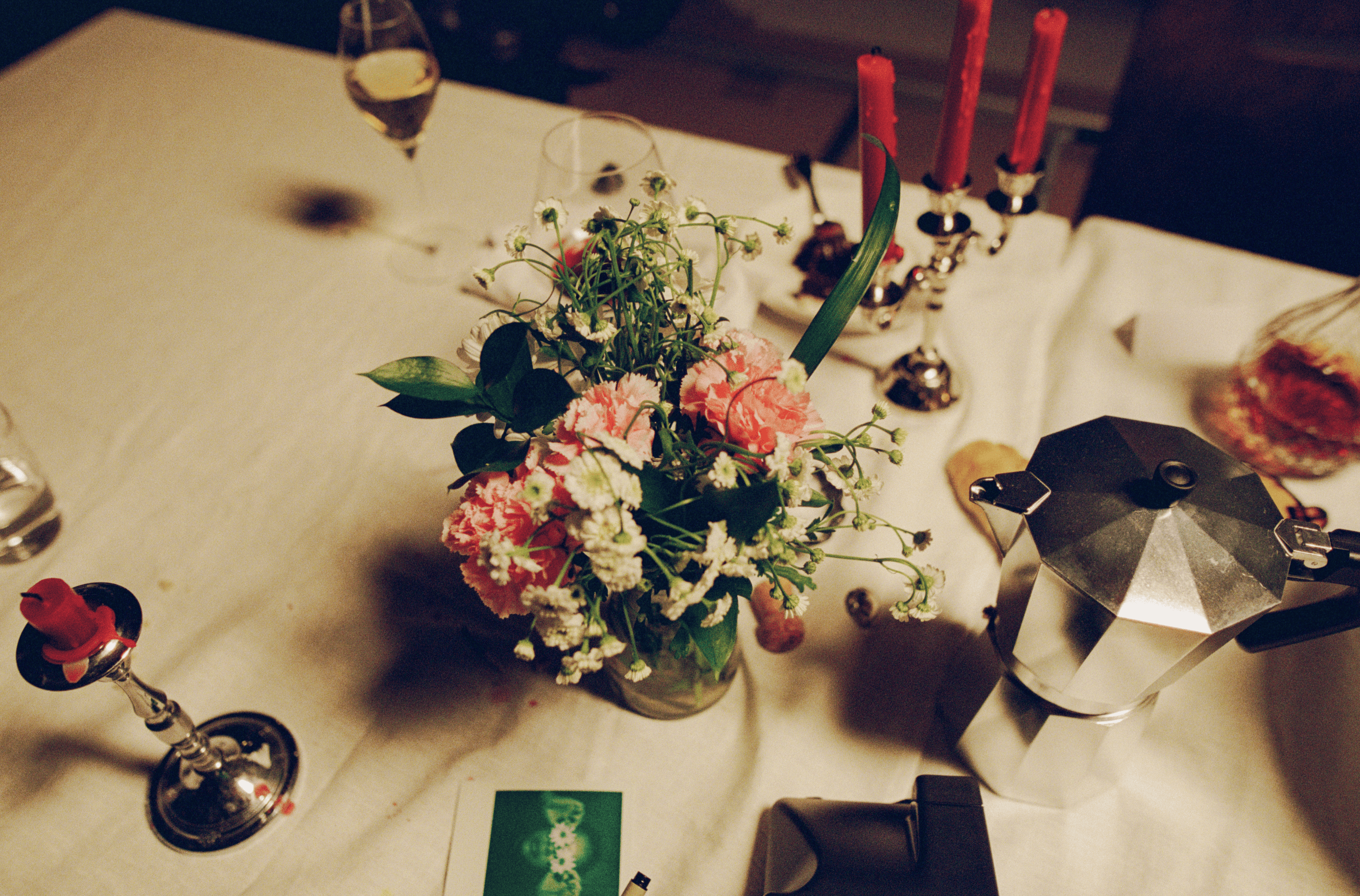 A decorated table with a floral tablecloth, featuring two vases of flowers and several blank white cards displayed behind.
