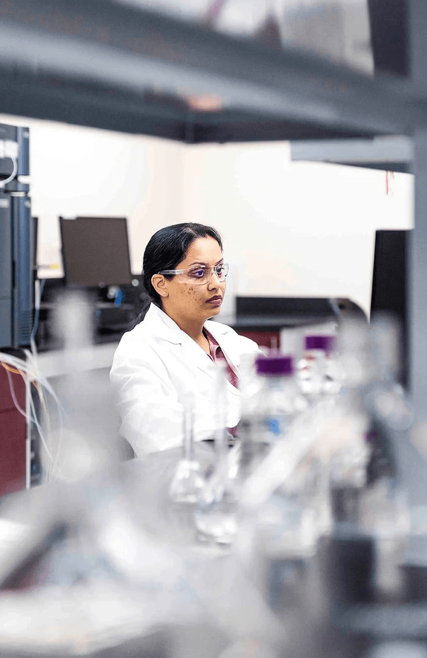 A SteriMax scientist in a lab coat and safety glasses, focused on a computer monitor in a laboratory.