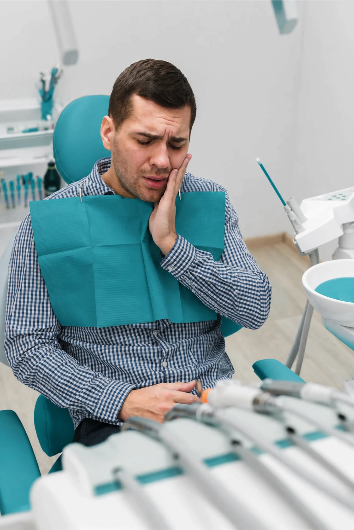 Patient wearing a dental bib receiving a checkup or treatment in a modern dental office setting.