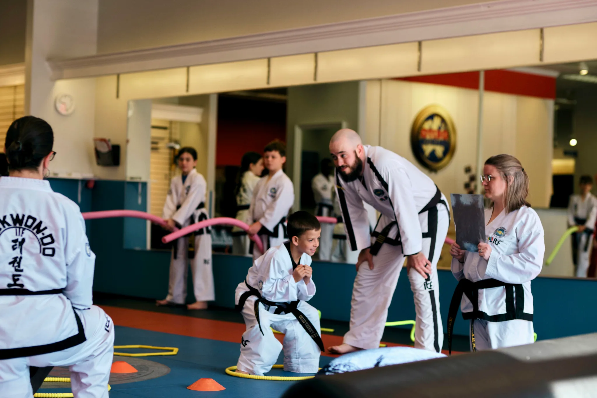 Martial Arts class with black belts and student completing an obsticle course