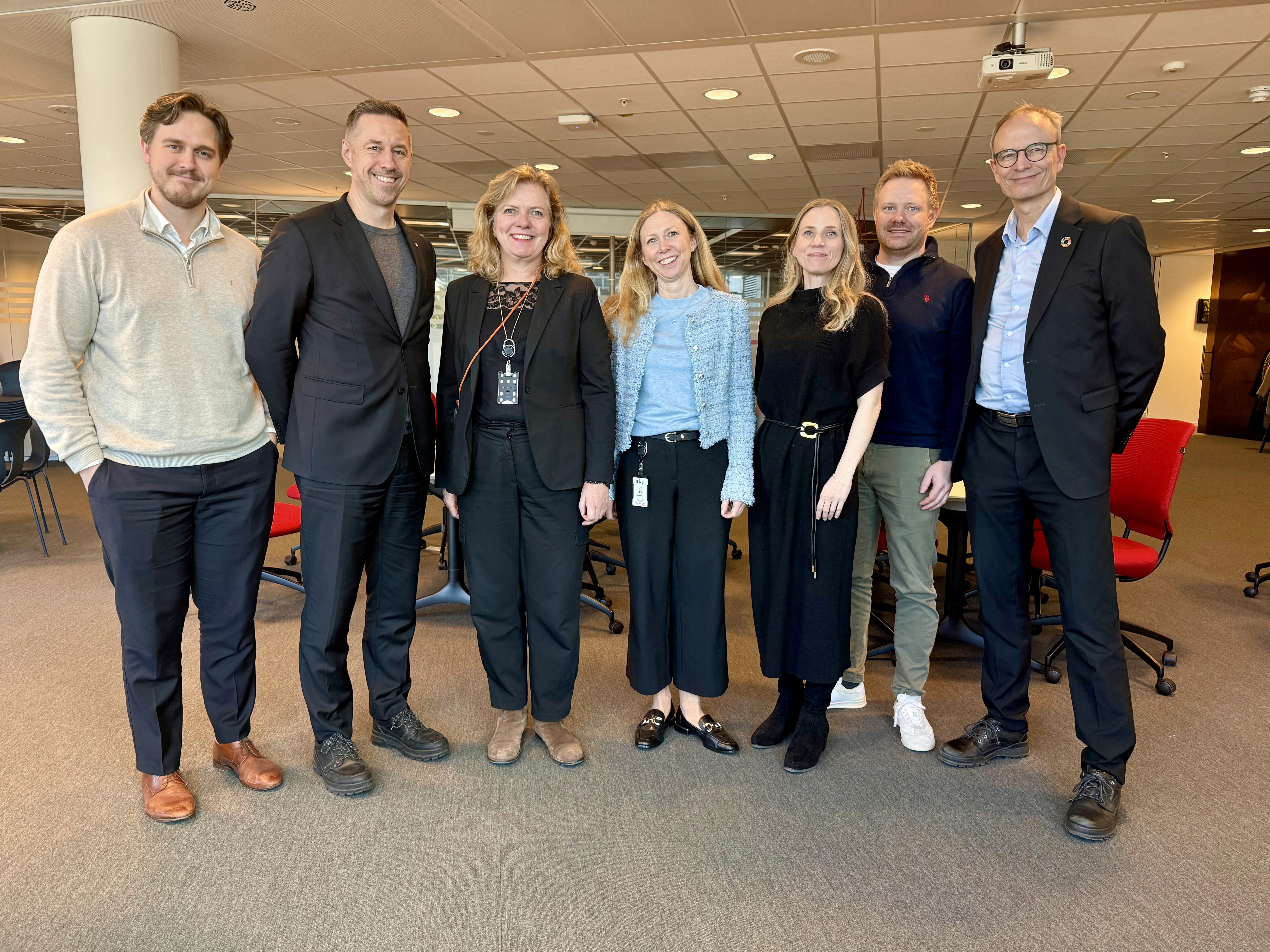A person wearing a virtual reality headset stands in front of multiple screens, engaged in a digital experience.
