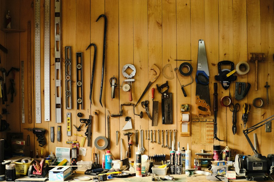 Wall of hand tools hanging above a cluttered workbench