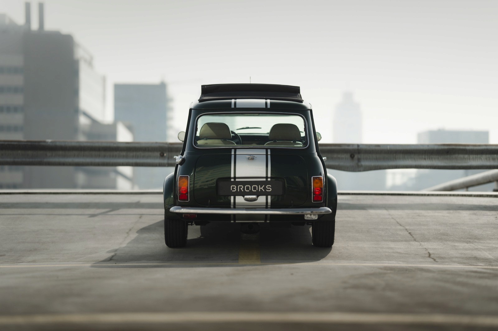 Classic car parked on a rooftop, with a city skyline in the background, showcasing sleek design and details.