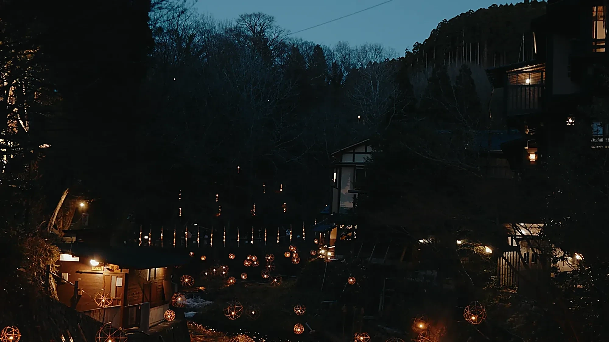 Yuakari seen from above at blue hour, the inns lit along the river at Kurokawa Onsen