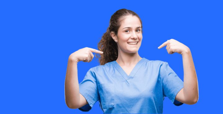 Smiling healthcare worker in scrubs pointing at herself on a blue background