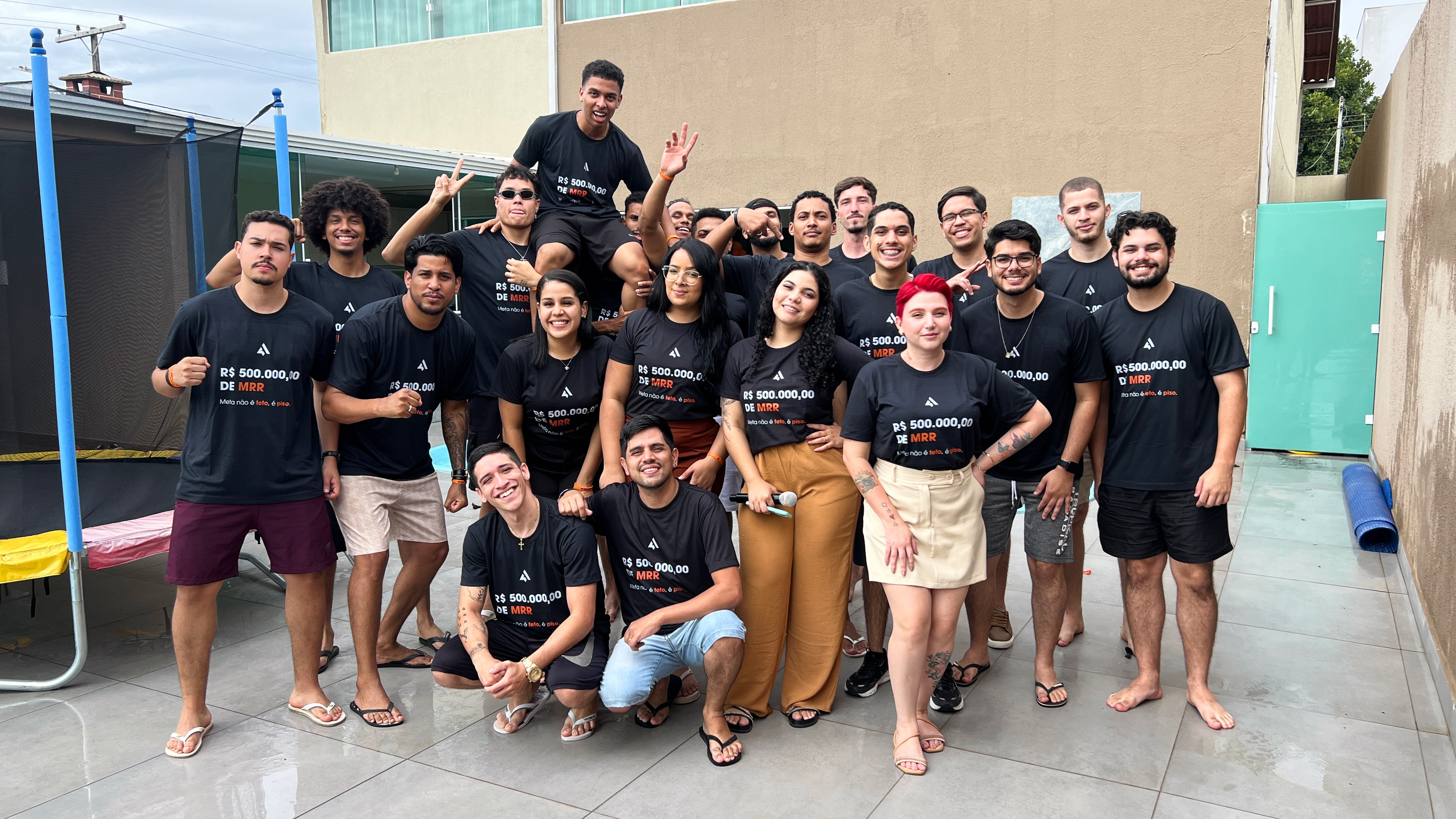 Equipe de profissionais reunidos ao ar livre, vestindo camisetas com metas de MRR, demonstrando união, crescimento e cultura de alta performance empresarial.