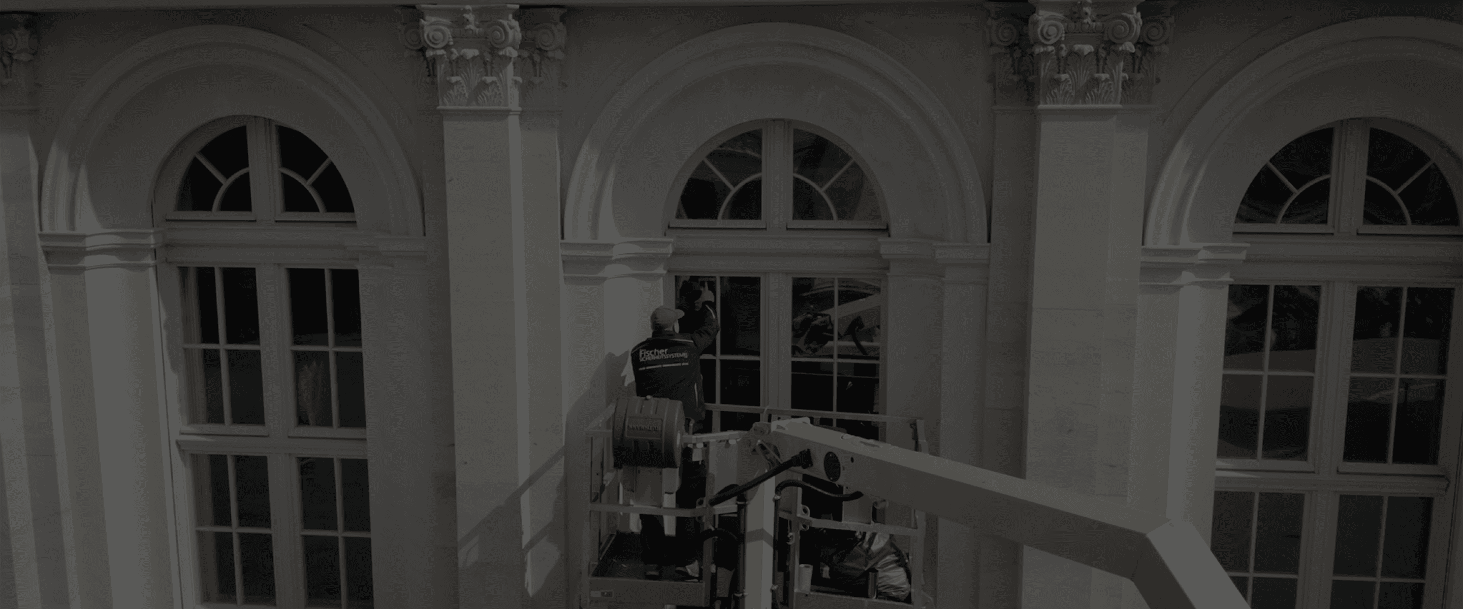 Ein Monteur arbeitet an einer großer Gebäudefassade.