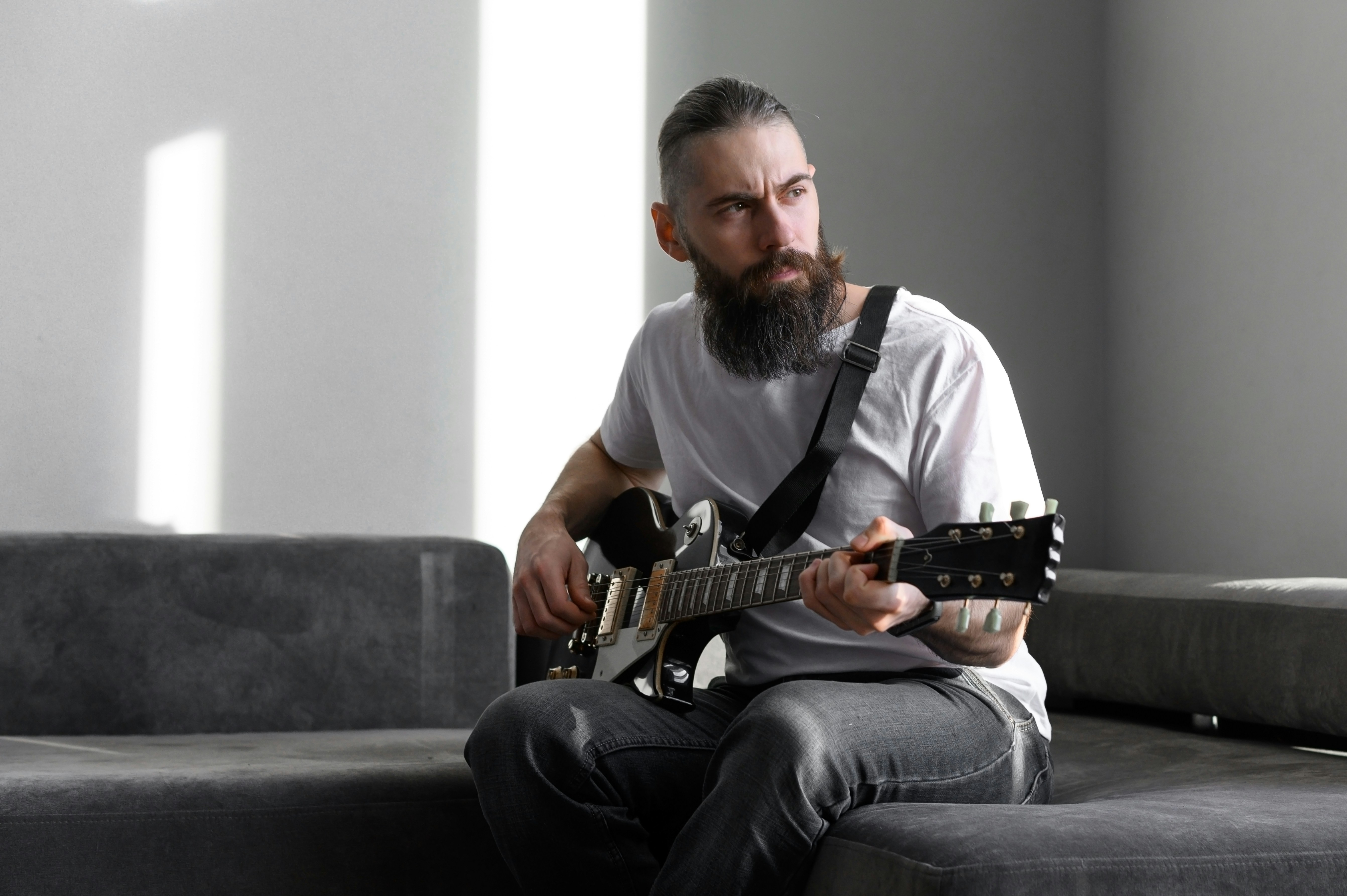 Man staring out the window with an electric guitar in his hand