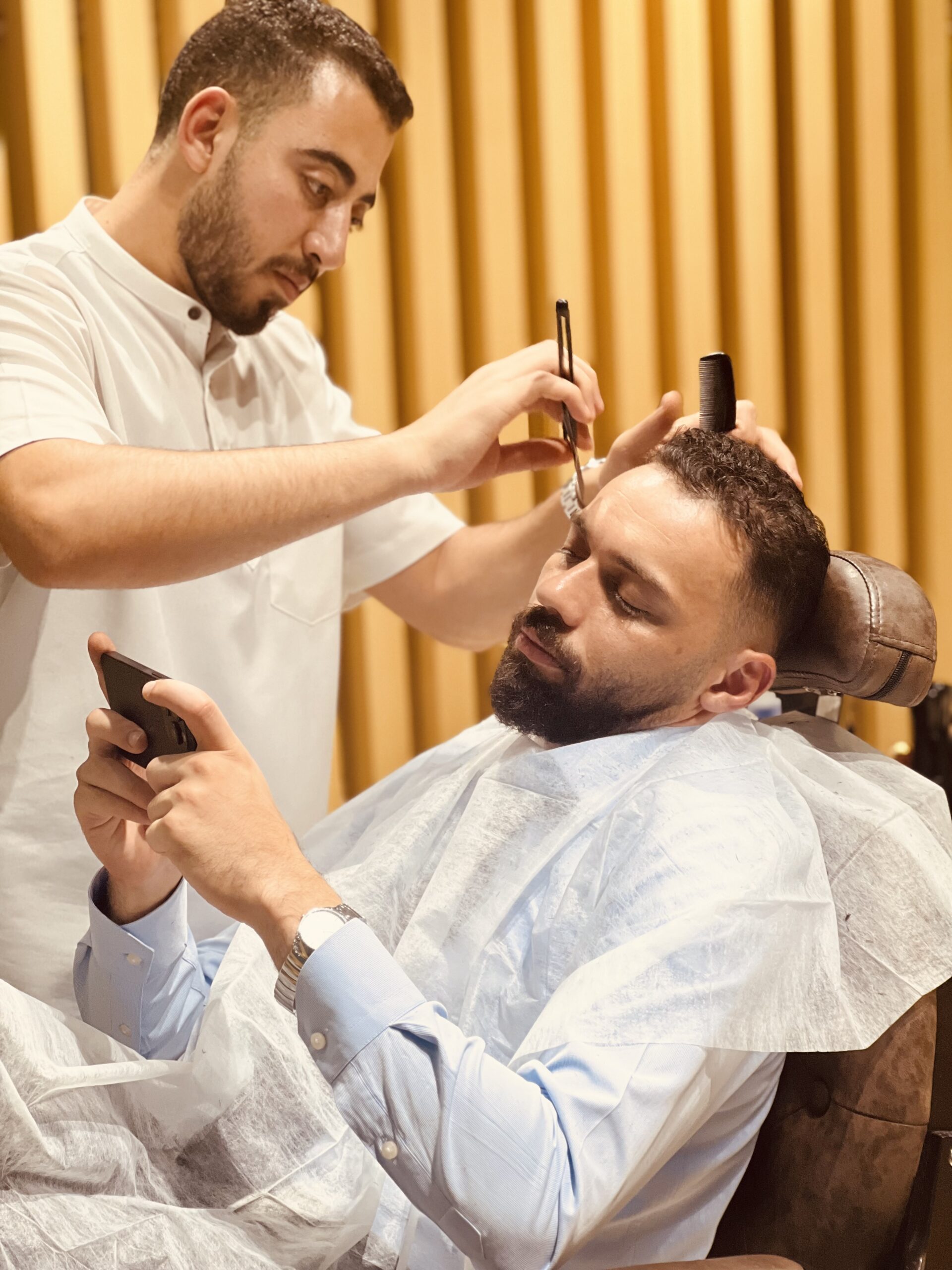 Barber giving his client the best haircut at the barber castle dubai, arjan.