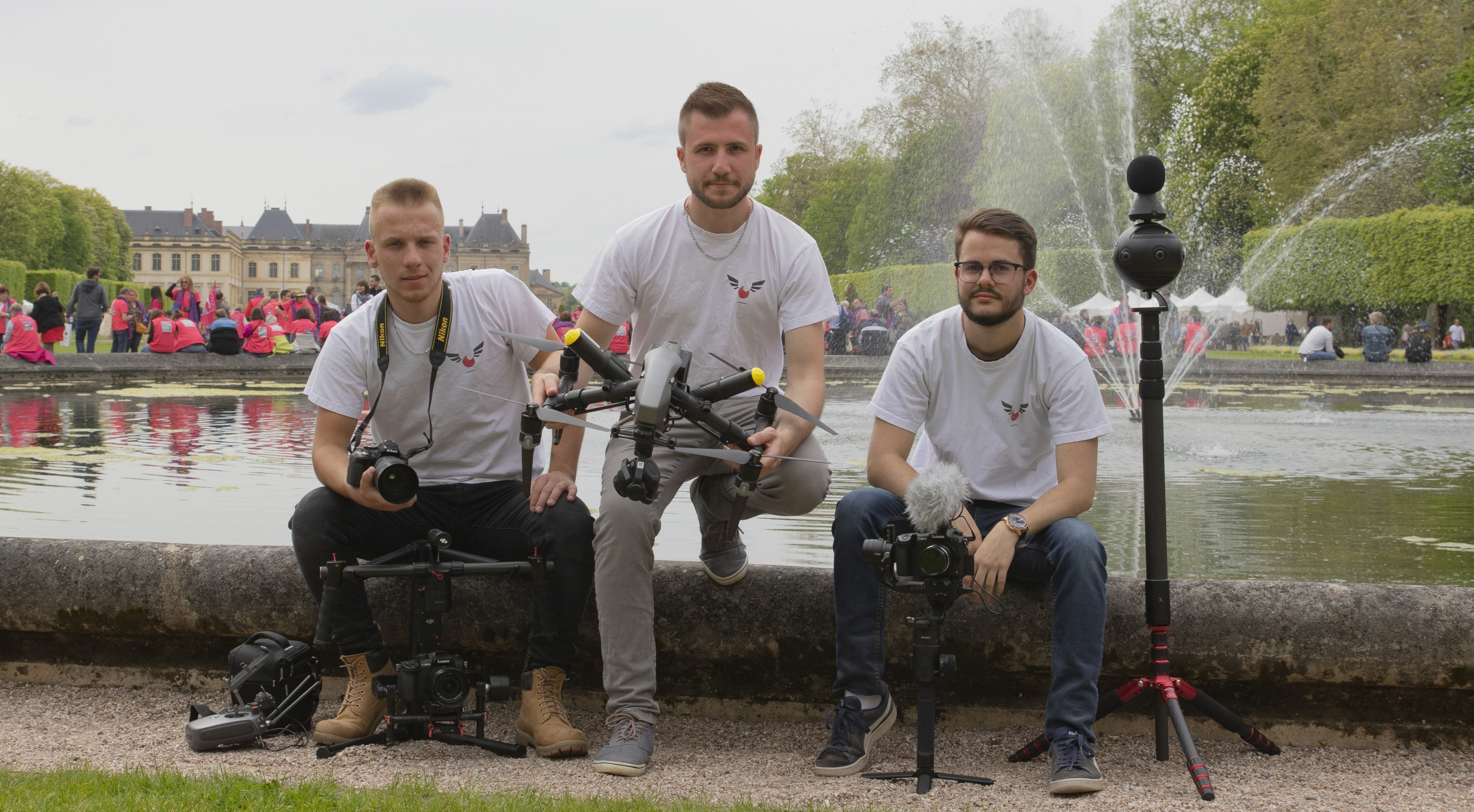 Two filmmakers operate a large camera on a dimly lit set. One wears headphones, both focused, suggesting a serious, creative atmosphere.