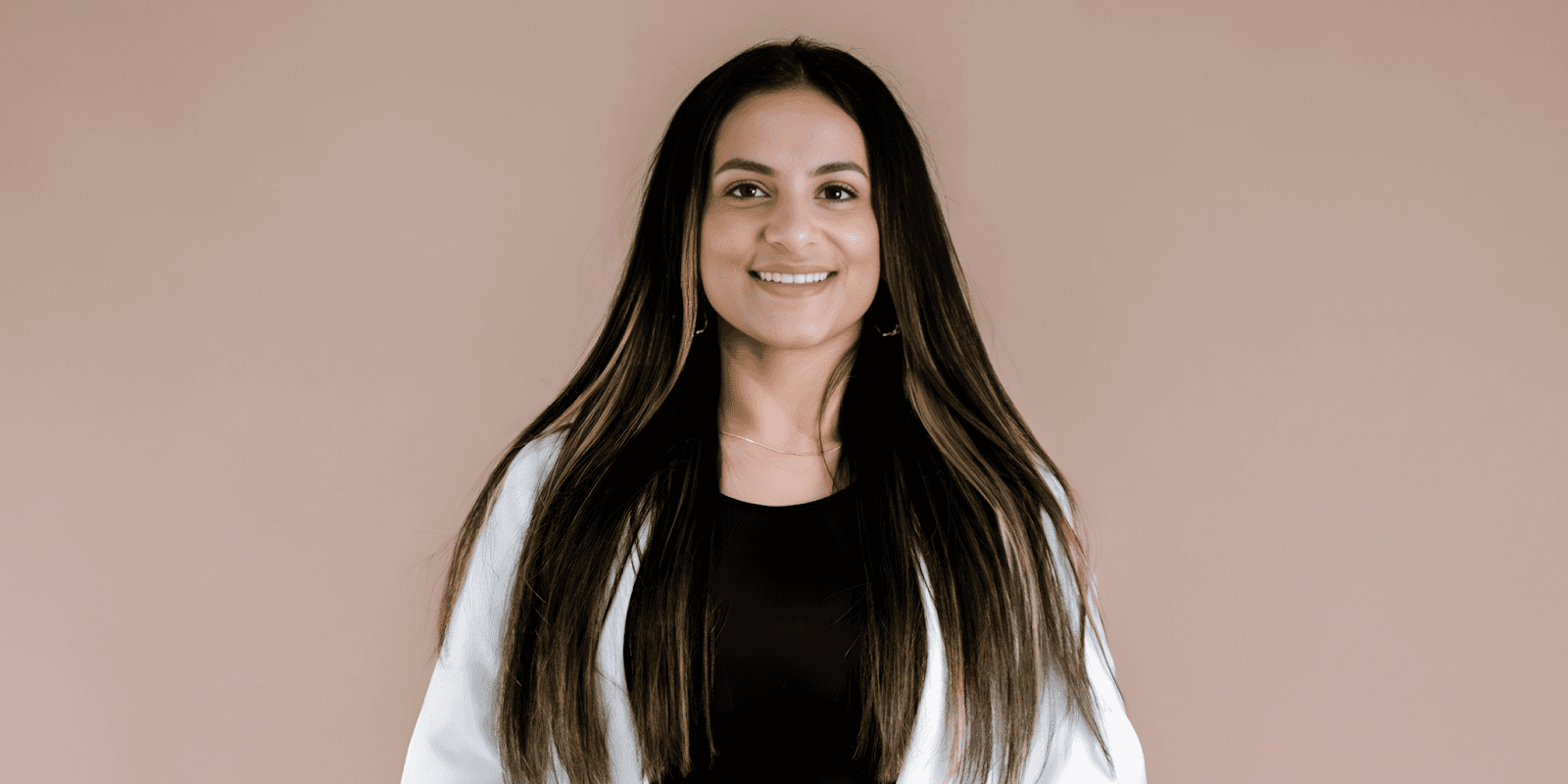 Aneeqa Mahmood, UGC creator and trauma therapist, smiling in a professional, warm pose against a simple neutral background.