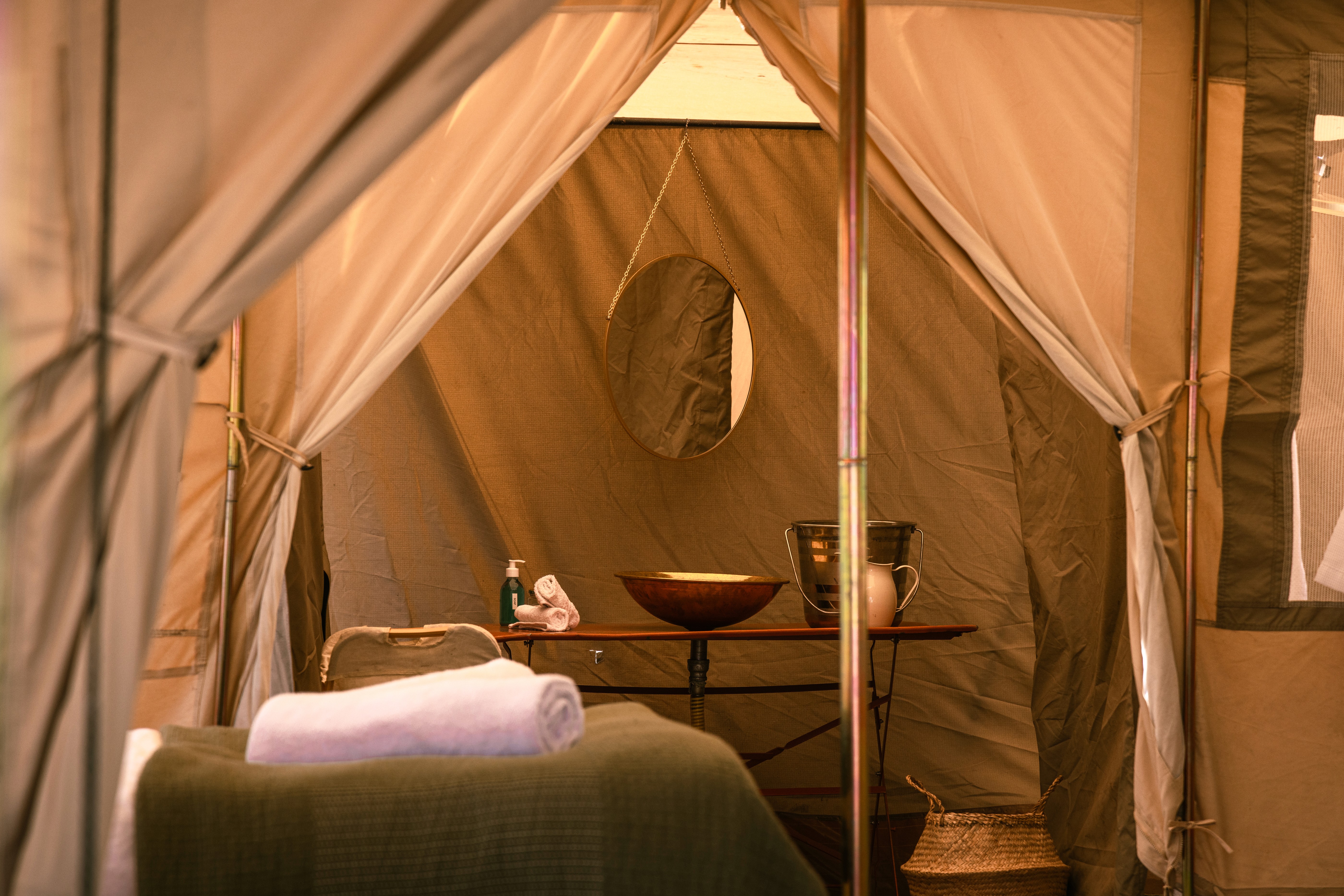 Kujwana Delta Ride, Okavango Delta, Botswana. Estetisk närbild som visar insidan av vackert glamping-tält med säng i förgrunden och ensuite badrum