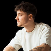 Young man working on laptop, focused expression. Indoor workspace.