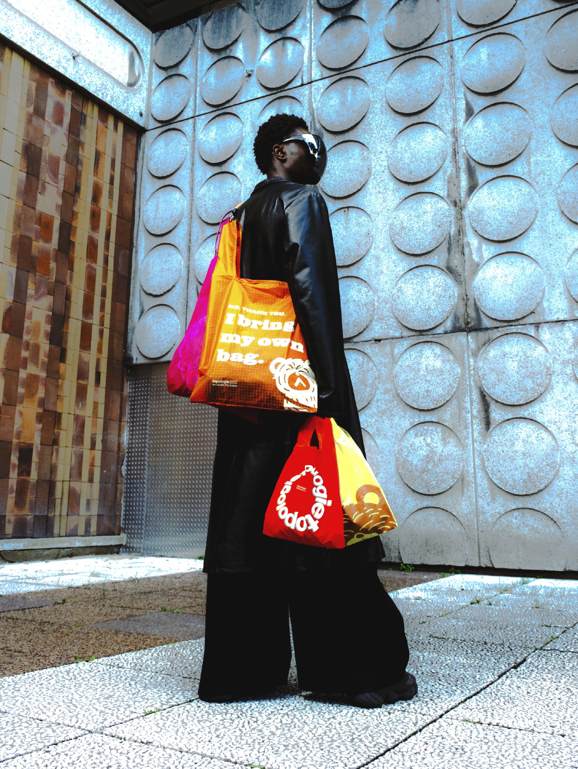 Vu de dos, un homme porte des sacs inspirés par les sacs du supermaché kombini au japon