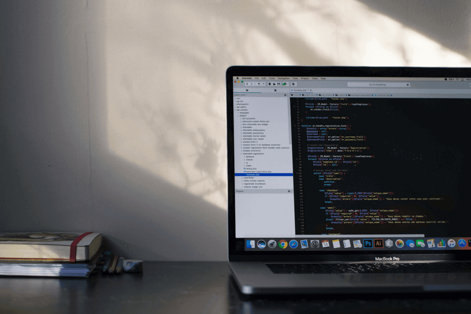 An open laptop and a notebook on a desk in evening light