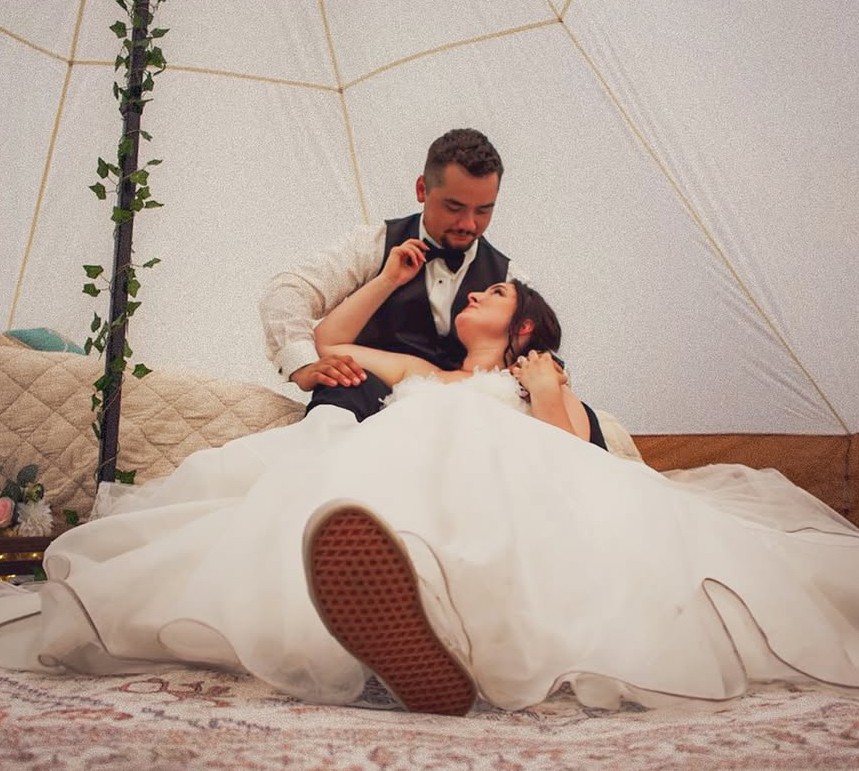 A bride and groom share a kiss surrounded by a joyful bridal party.