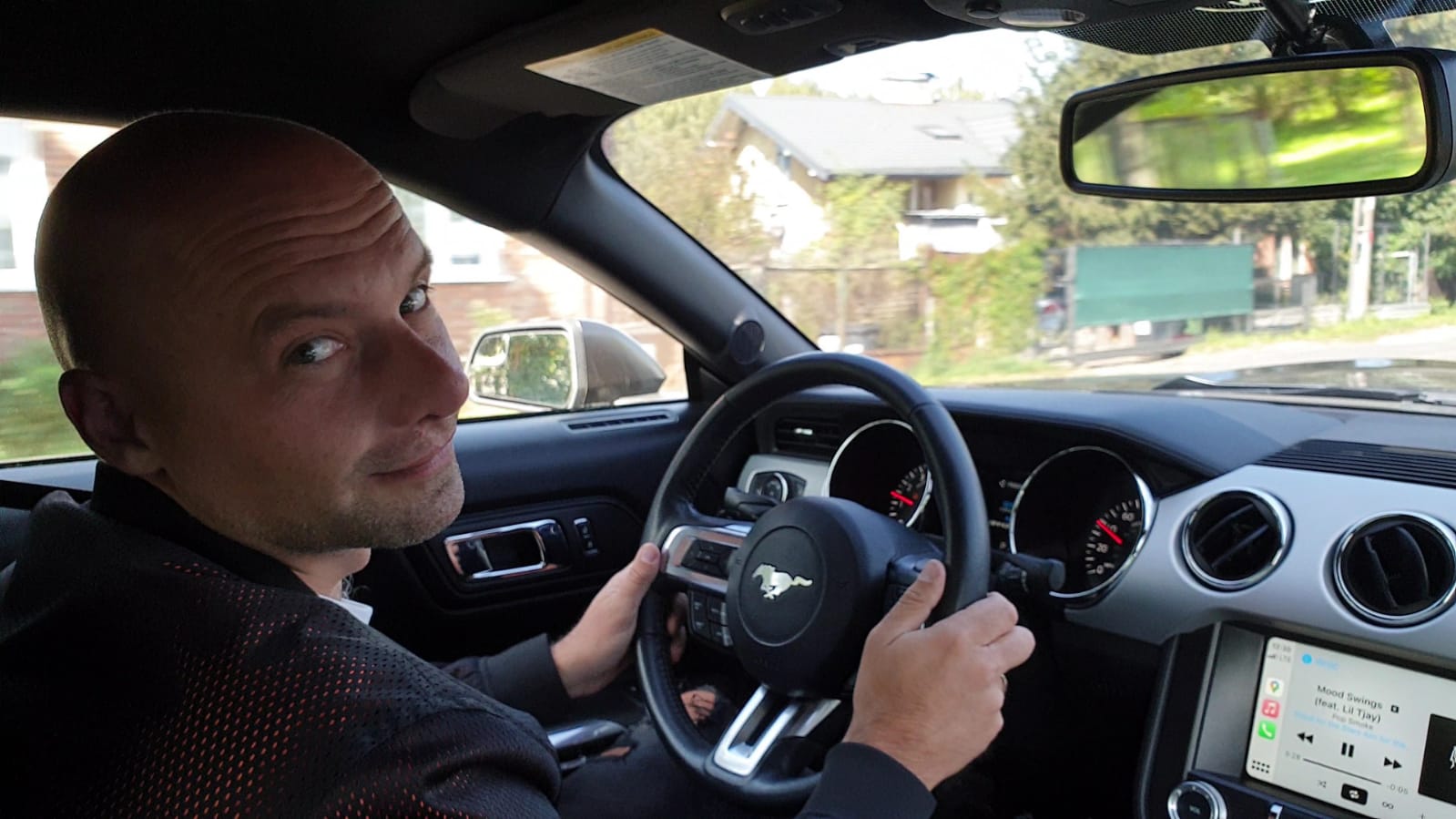 Krystian Orlikowski – Instruktor w samochodzie, patrzący w stronę aparatu z uśmiechem.