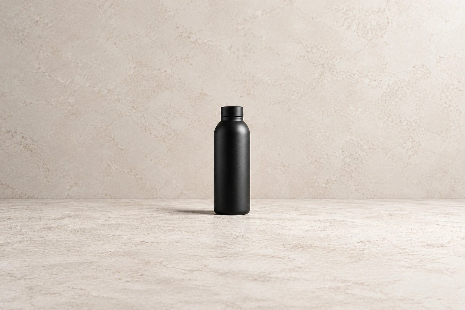 Unbranded matte black bottle on a pale stone studio surface with a soft contact shadow
