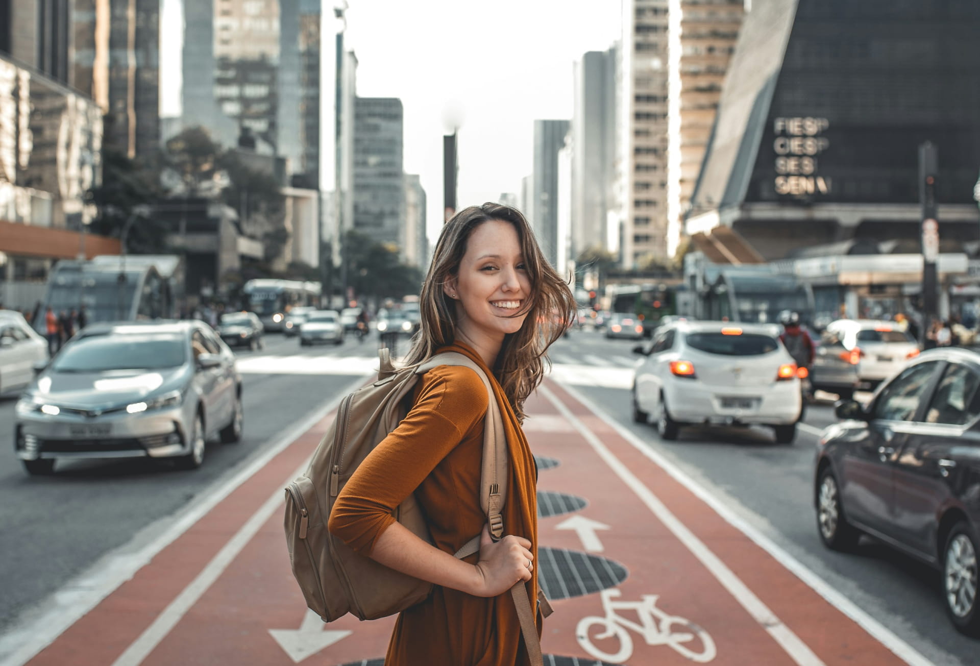 A woman with a backpack stands on the road