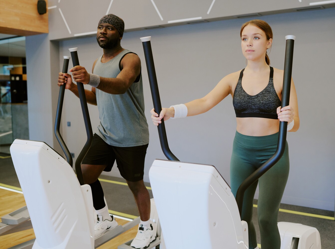 young couple doing a HIIT elliptical exercise for weight loss at a sleek modern gym