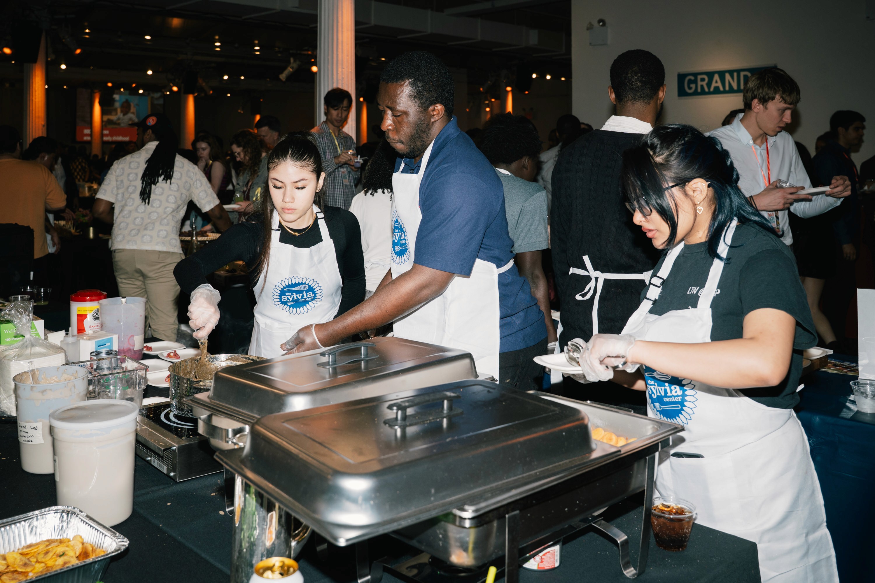 Student chefs preparing food in a crowded event space