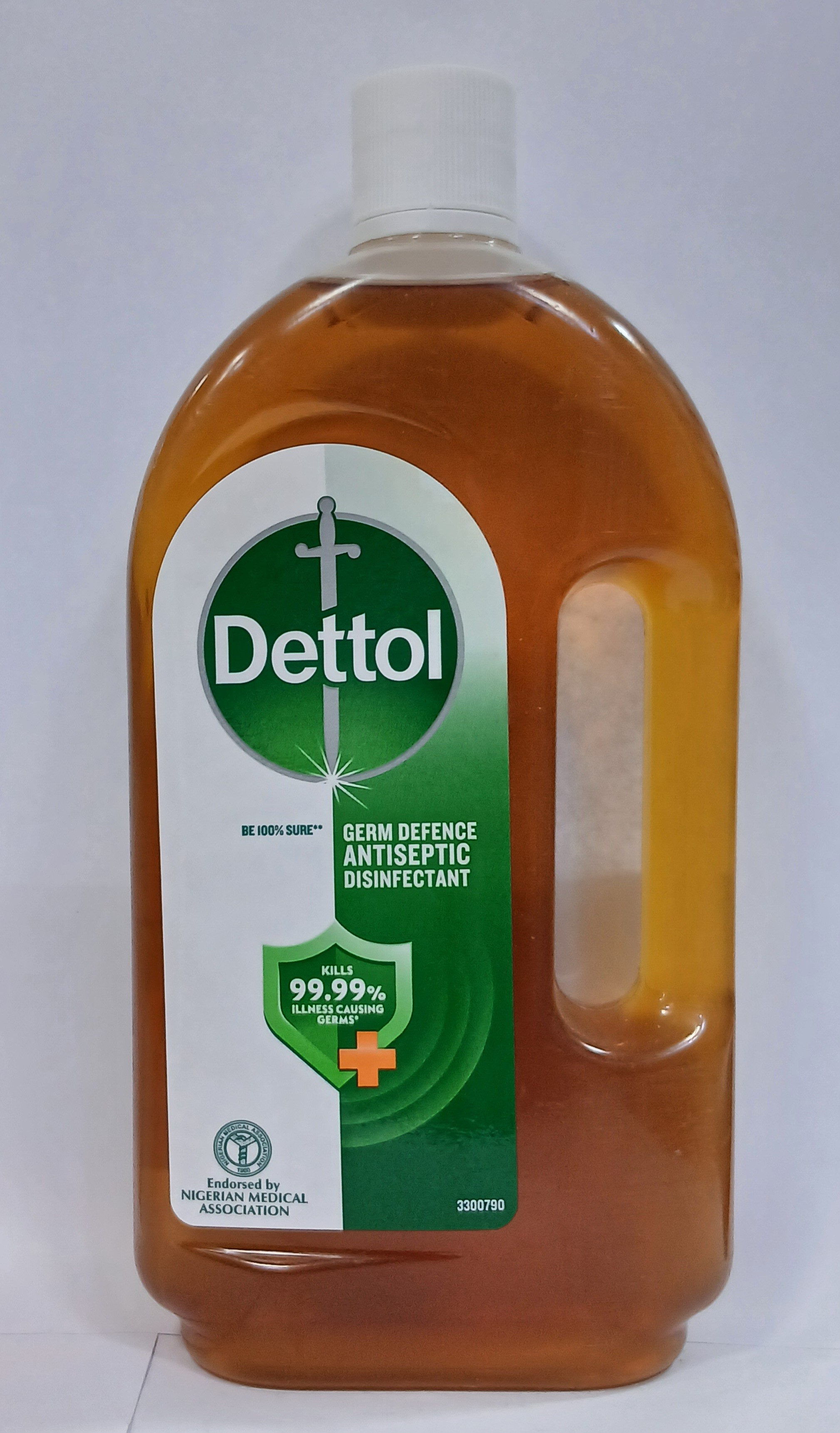 A large amber plastic bottle with a green label featuring a white cross symbol and text stands upright against a plain white background.