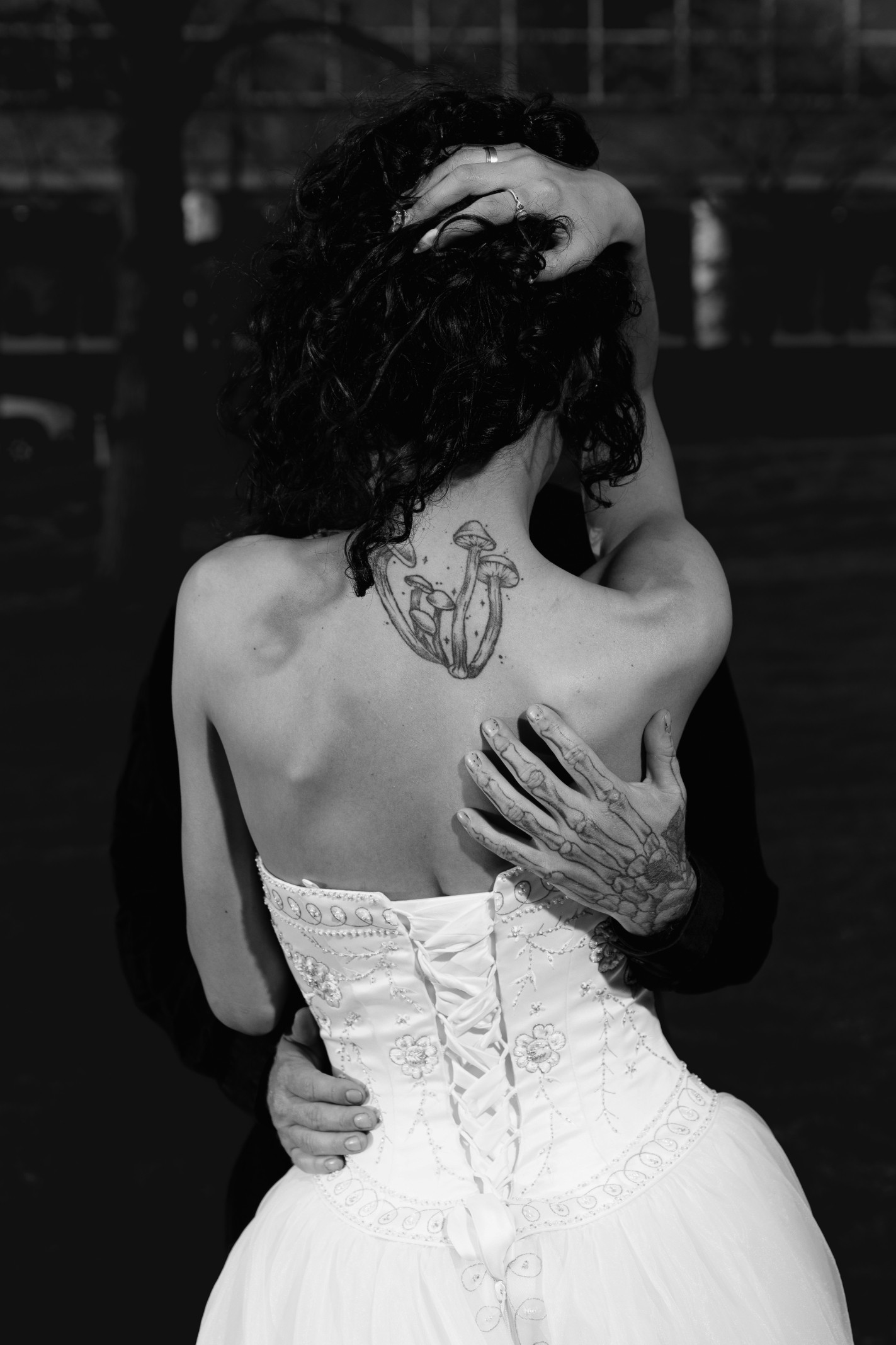 A couple stands hand-in-hand in front of a rustic stone building.