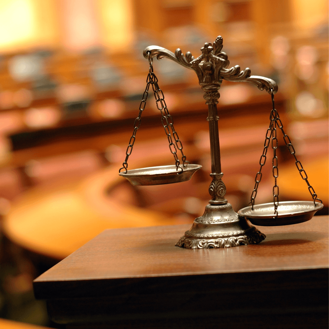 An office setting where a lady is bent over and talking to another lady seated while a man is bent over on the other end to another woman seated.