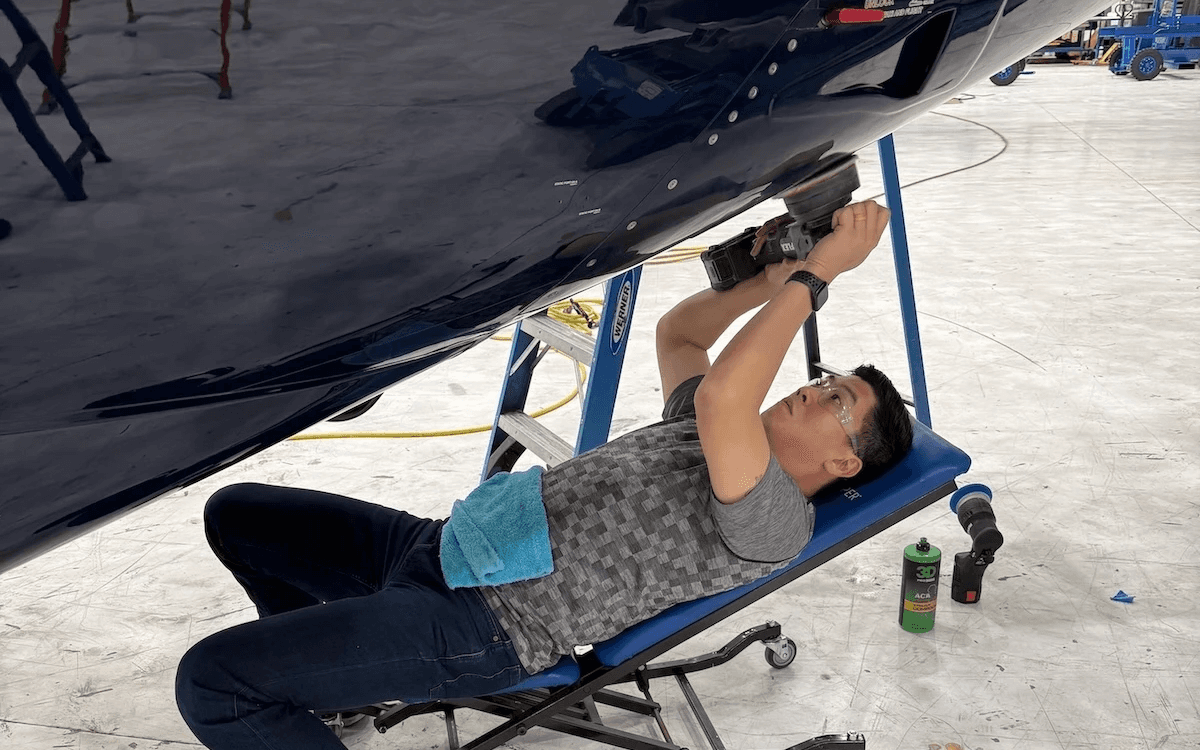 Aircraft detailer cleaning the underside of a private aircraft