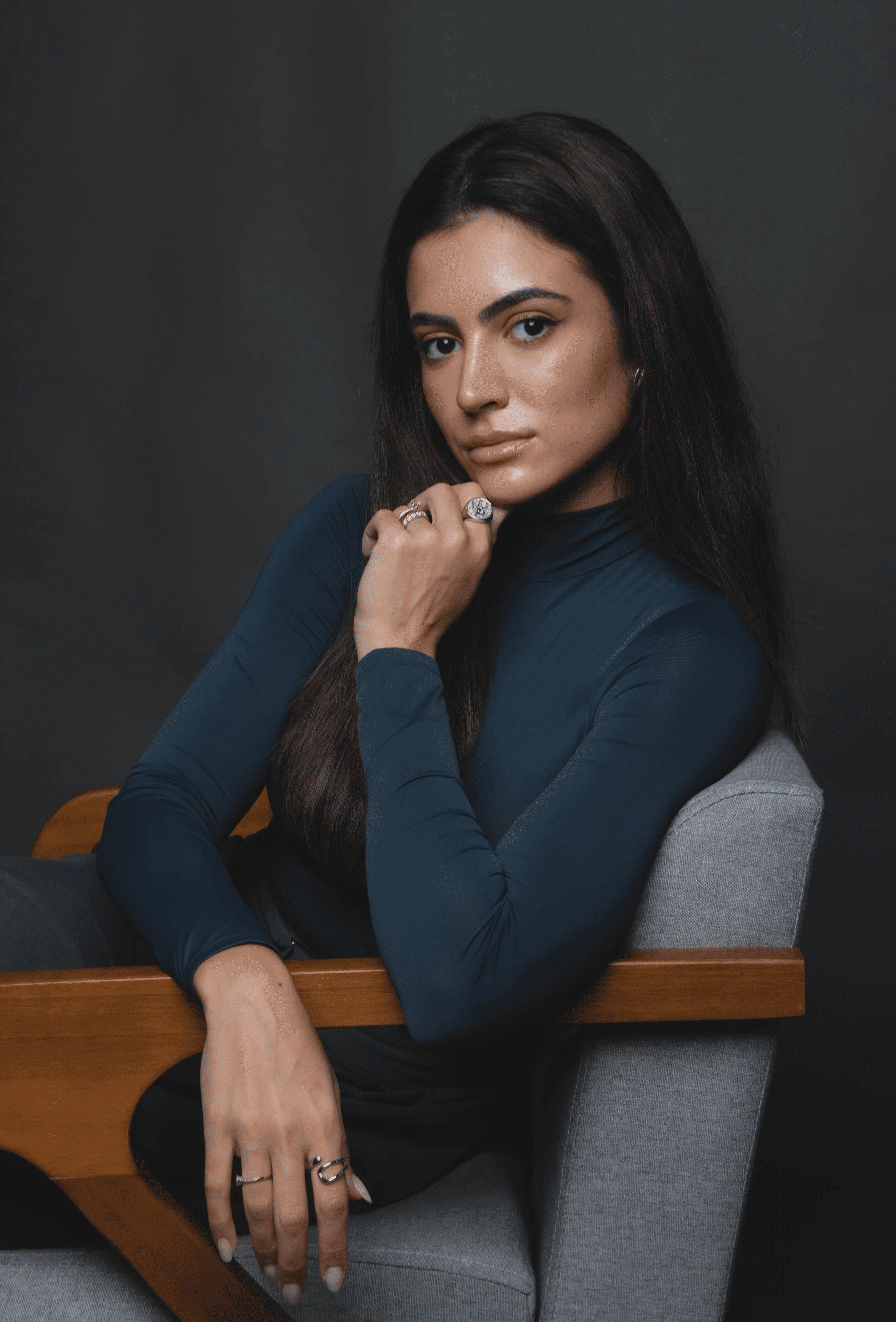 Smiling female therapist with short gray hair, wearing a brown top and a purple shawl, surrounded by a cozy background.