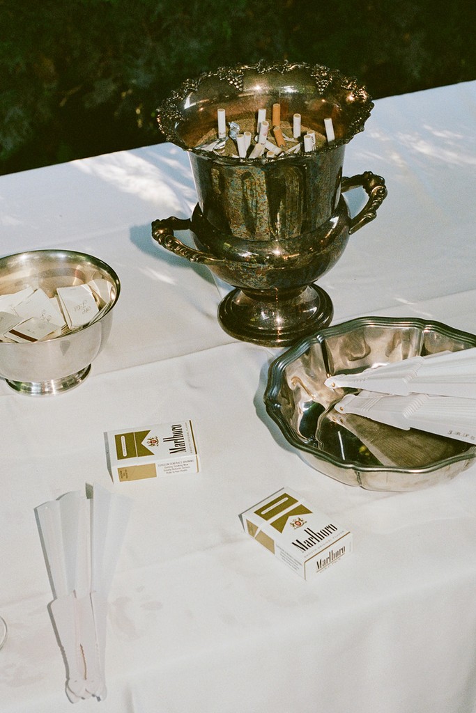 Vintage wedding reception detail with silver bowls, matches, and cigarettes on a white tablecloth