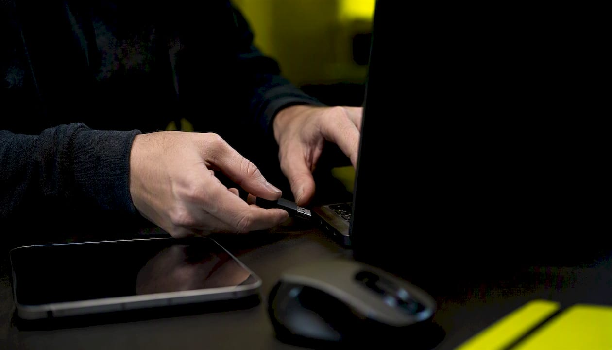 Hands managing USB key at dark tech desk