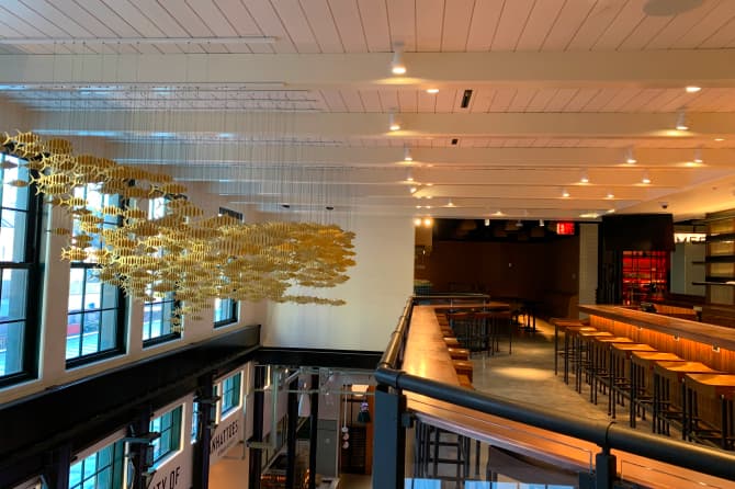 Hanging art mobiles over a lobby and a warmly lit bar on the second floor loft