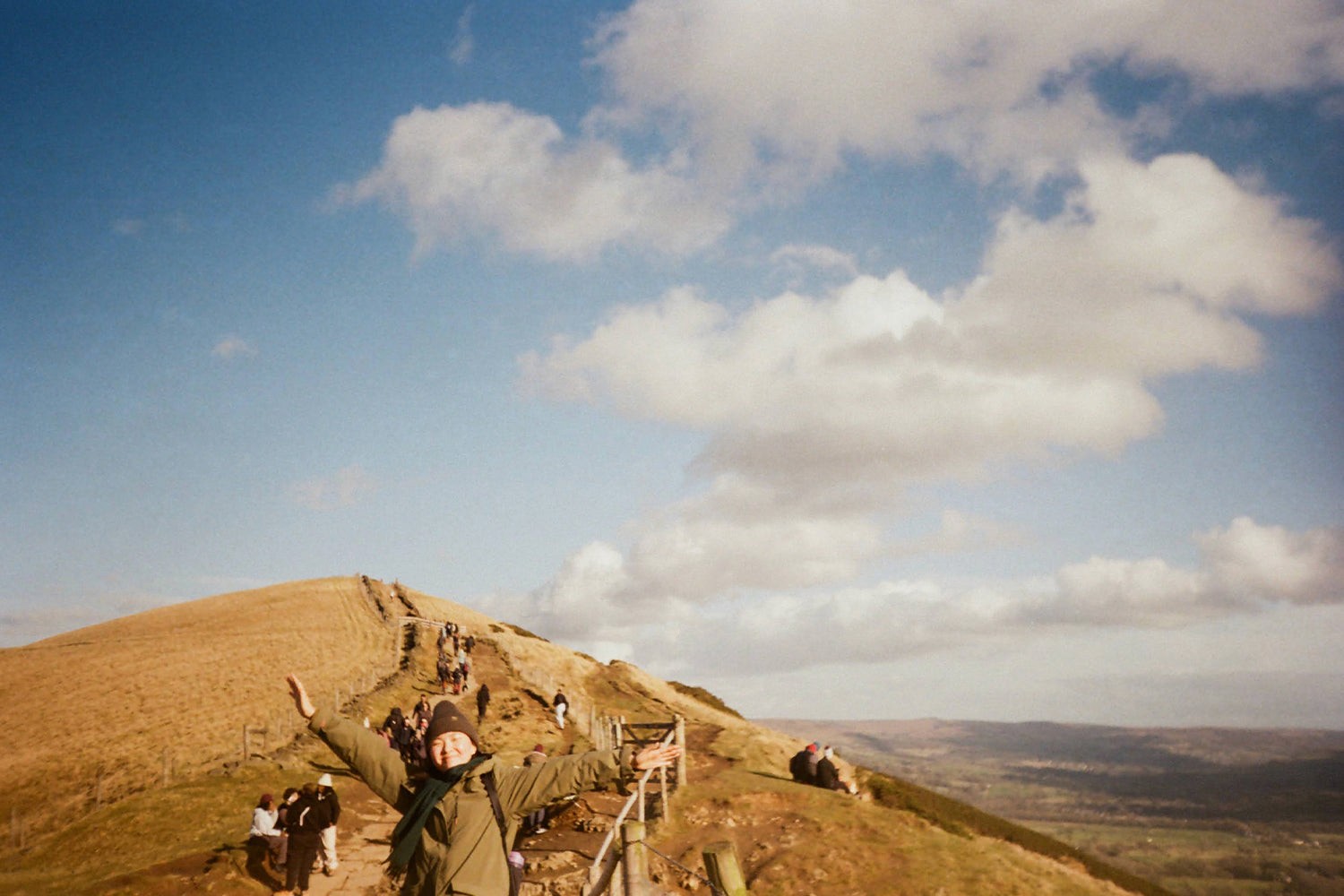 A person with arms outstretched on a hillside pass