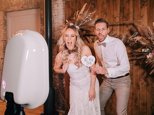 Bruidspaar staat samen voor de photobooth een foto te maken.